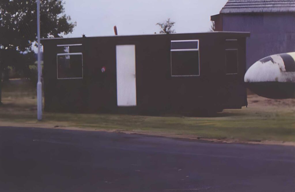 The Solway Aviation Museum first home, a wooden cabin with a white door.